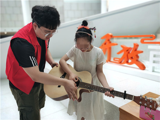 志愿者教她弹吉他.jpg